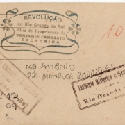 Verso da fotografia / Acervo do AHRS

Marcas de carimbos no verso da fotografia. Uma fonte rica para analisar a trajetória da fotografia, desde sua produção até seu acondicionamento em espaços de memória. Através desses registros sabemos que essa fotografia, que depois foi reproduzida, foi realizada por Benjamin Camozato quando na produção do filme “A Revolução no Rio Grande” em 1923. Por essas marcas, se sabe, também, que estiveram no acervo do Instituto Histórico e Geográfico do RS e no Arquivo Histórico do RS, onde estão atualmente.
